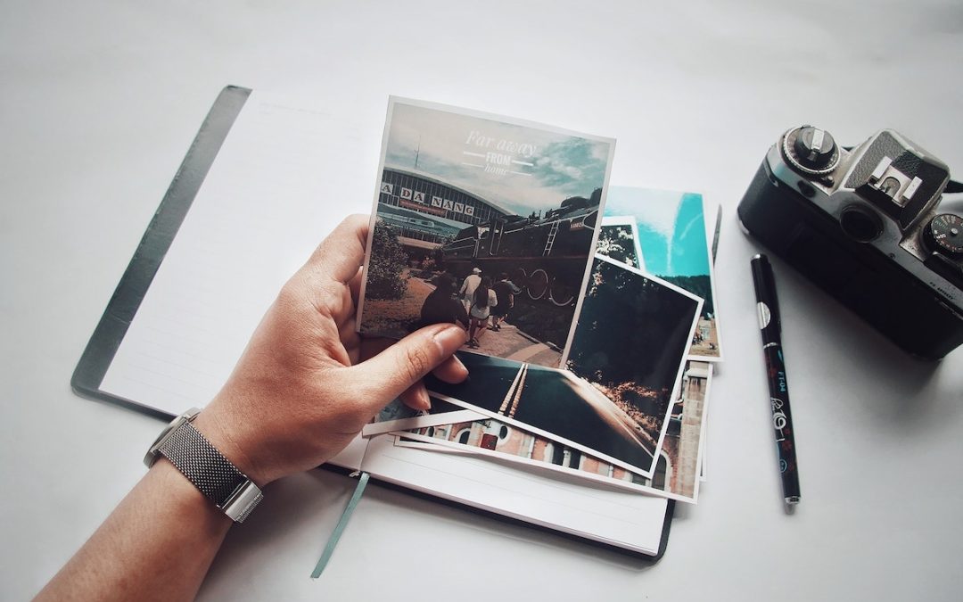 A hand holding a camera and a notebook, capturing party photos for Personal Touch Printing and Christmas cards.