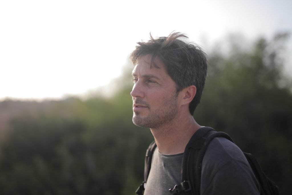 A man with a backpack standing in a field, captured with photo printing on site.