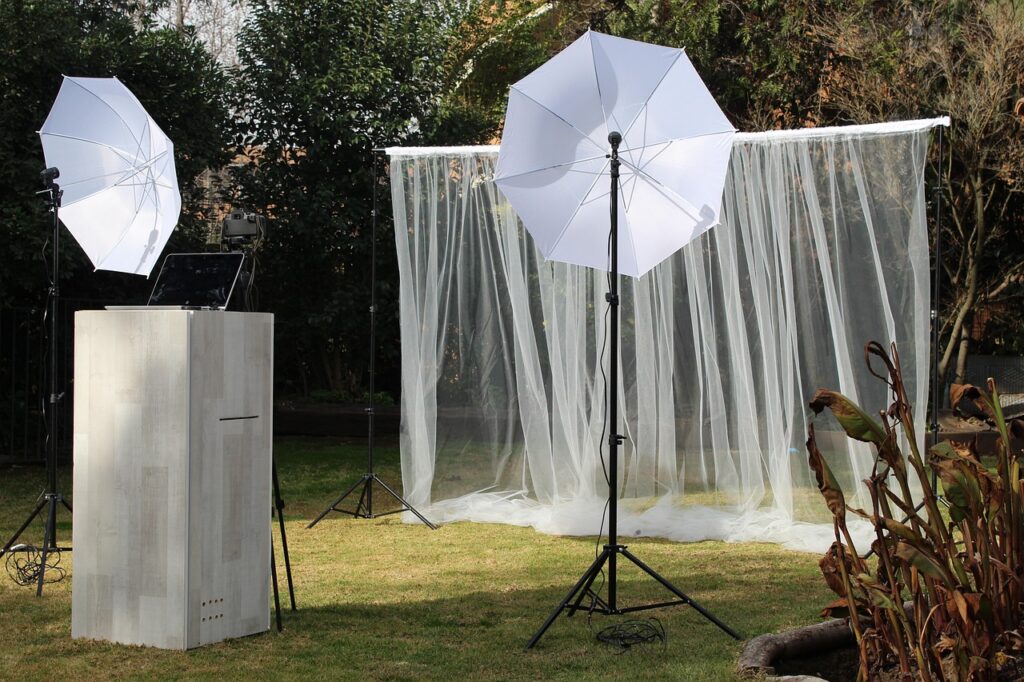 A yard photo booth with umbrellas offering photo printing and DVD showing.