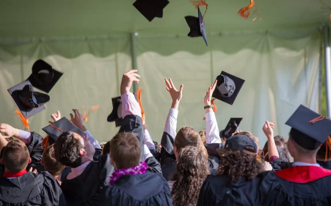 A group of graduates tossing their caps in the air, captured in a memorable photograph by Personal Touch Printing.