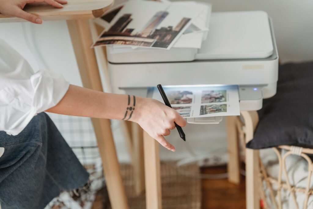 A woman is using a printer to print photos for Memorial Programs.