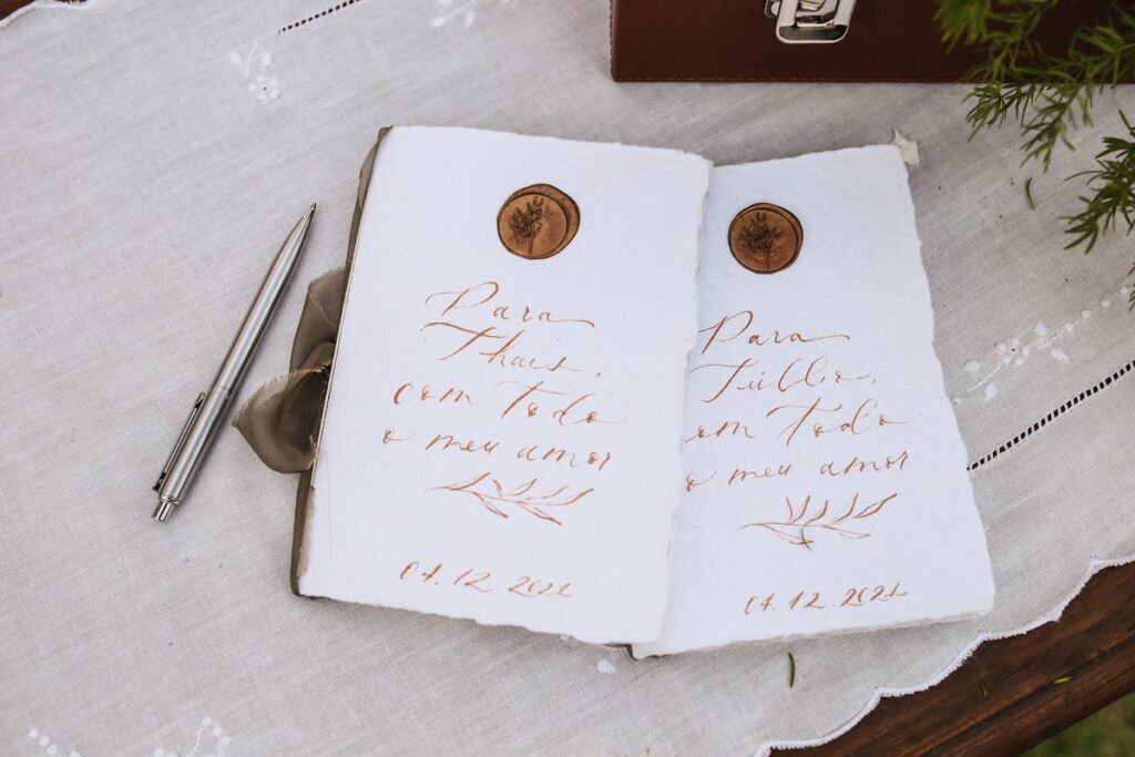 An open journal with handwritten vows and two rings on a table setting at a wedding ceremony, ready for photo printing to capture the moment.