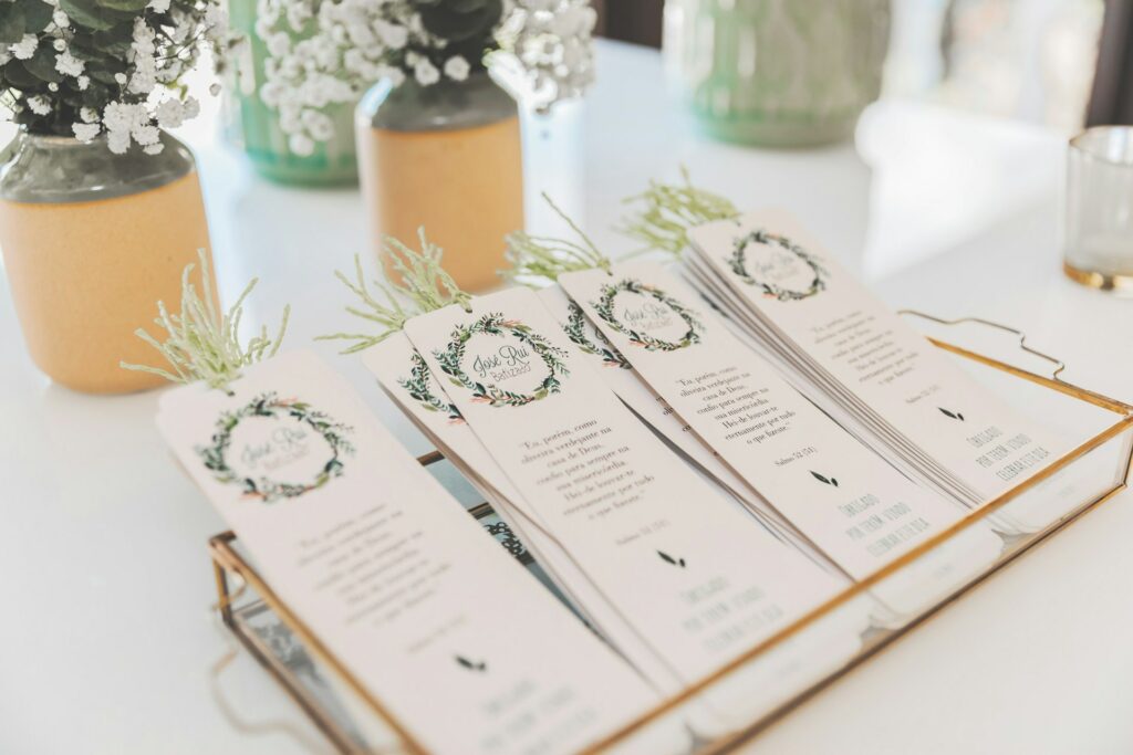 Elegant wedding menus laid out on a table with decorative flower arrangements and a DVD showing in the background.