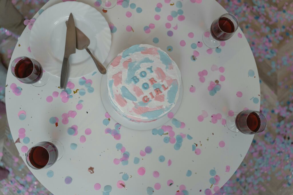 The cake with "Boy or Girl?" text on top, surrounded by confetti and four glasses on a round table, suggests a gender reveal party. Personal Touch Printing can add an extra special touch to events like these with custom photo prints.